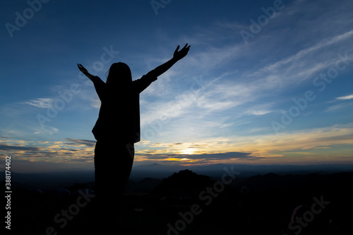 Silhouette of asian woman raise her arms looking at the mountain and enjoy with beautiful nature with freshness and happiness