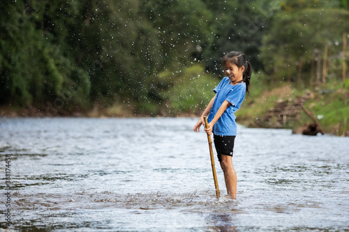 Happy asian child girl playing in the river with fun and enjoy with nature. © pingpao