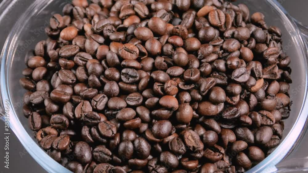Lots of roasted coffee beans lying in a round glass bowl Lots of roasted coffee beans lying in a round glass bowl
