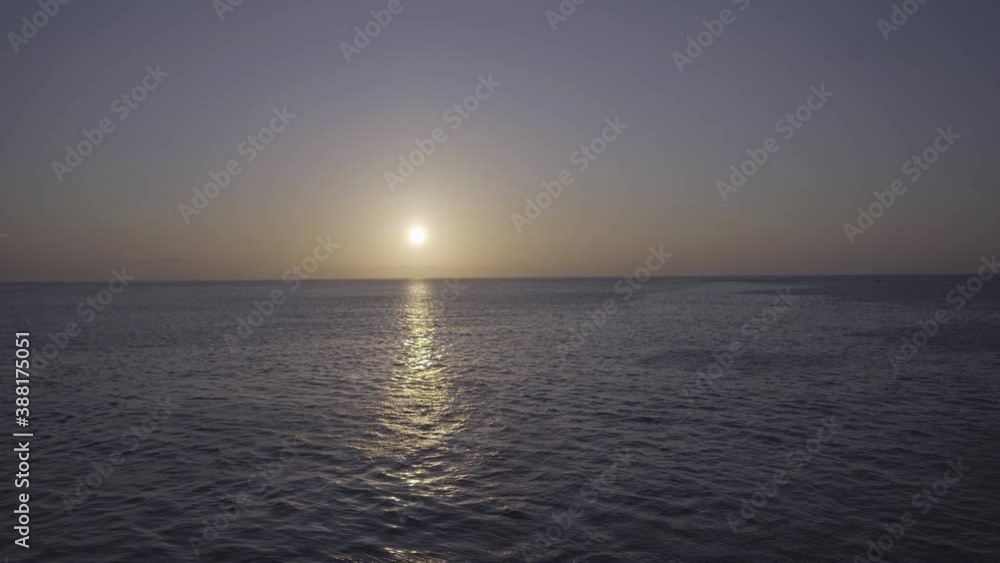 A sunset is being watched from the edge and railing of a cruise deck in the Galapagos islands. The water of the ocean is reflecting the sunlight. A sunset is being watched from the edge and railing of a cruise deck in the Galapagos islands. The water of the ocean is reflecting the sunlight.