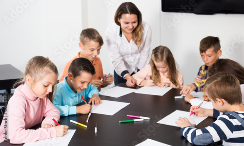 Group of children sitting at table with board game and dice at school class