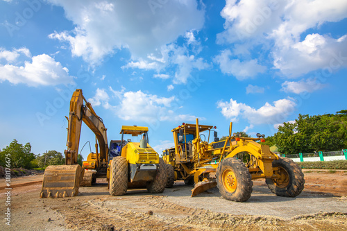 Backhoe, grader and road roller on the ground at site construction.