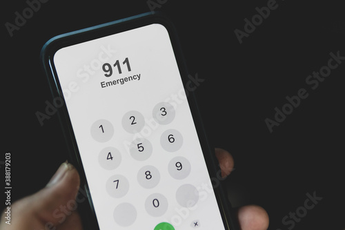 Quadro em tela Hand holding cell phone with emergency number 911 on black background