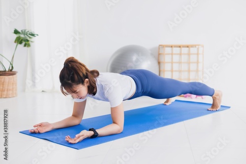 Asian beautiful woman exercise and play yoga at home.Concept of Exercise during the quarantine at home for preventing coronavirus and covid-19 infection.