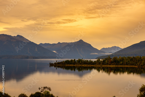 Beautiful Lake Te Anau scenery and water reflections under a vibrant orange coloured sky at sunset