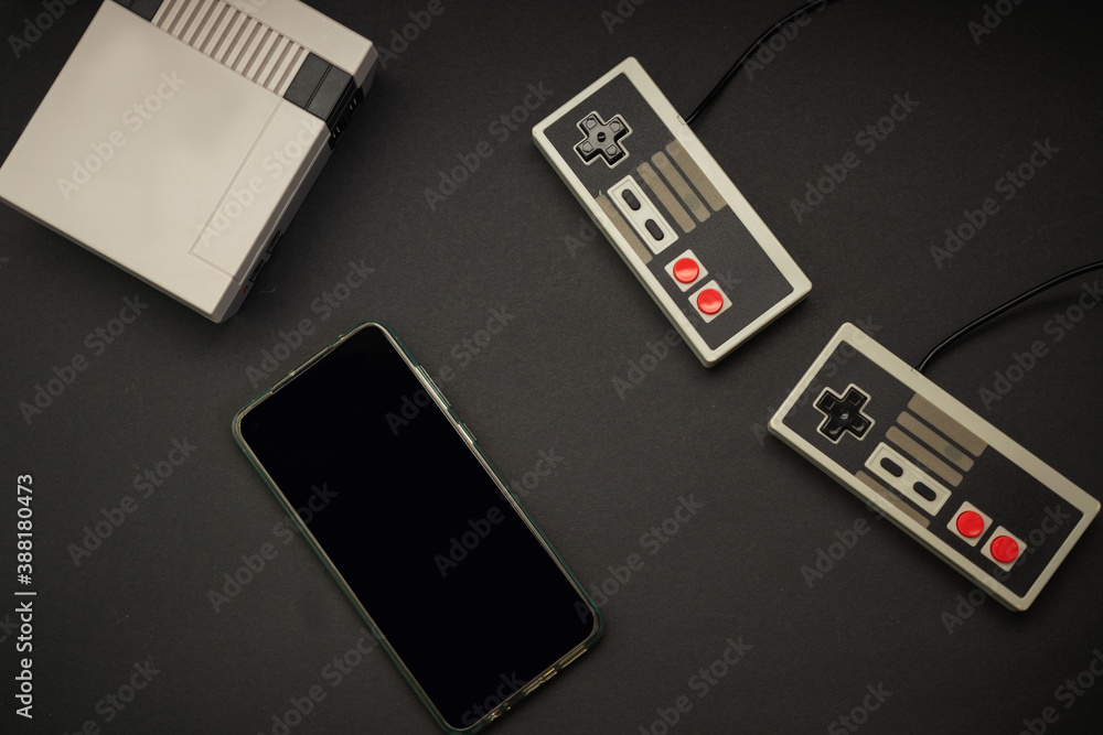 retro console and controls and cell phone on black background retro console and controls and cell phone on black background
