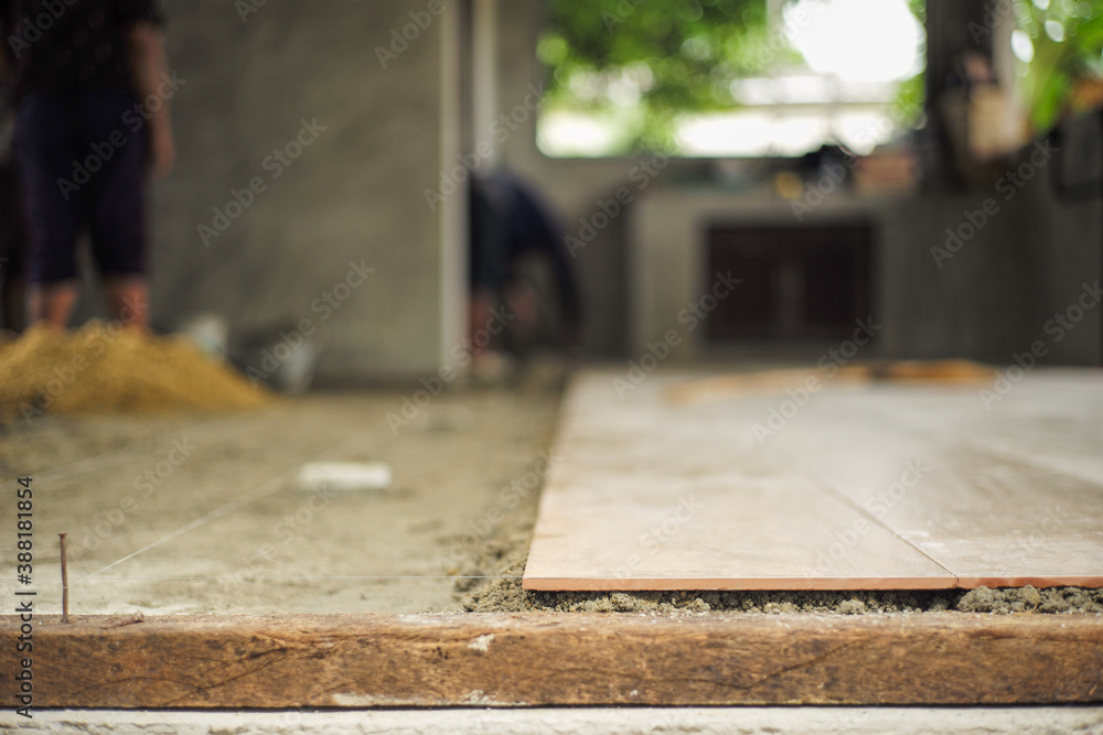 Closeup floor tiles on the mixed cement with nylon for levelling in the house under construction Closeup floor tiles on the mixed cement with nylon for levelling in the house under construction