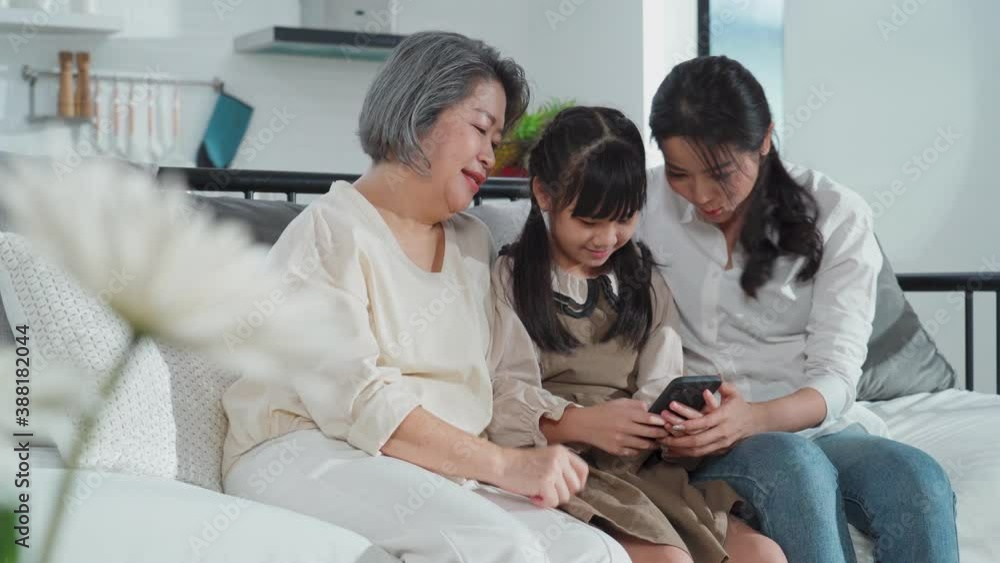 Asian grandmother and young mother looking at their child playing game Asian grandmother and young mother looking at their child playing game