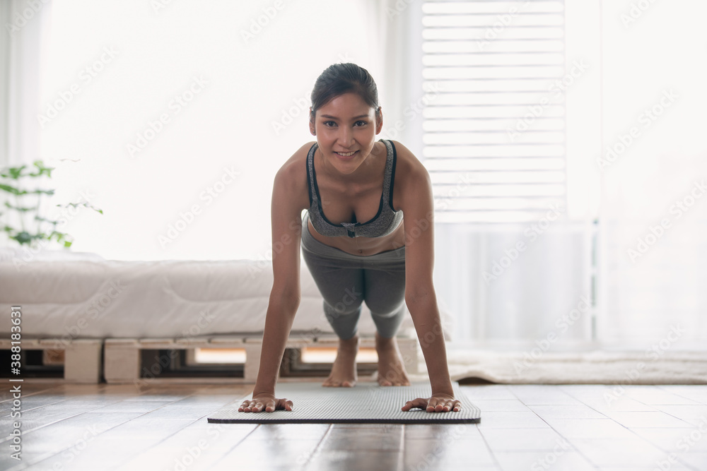 Fototapeta premium Attractive Asian woman practice yoga Plank pose to meditation in bedroom after wake up in the morning Feeling so comfortable and relax,Healthcare Concept