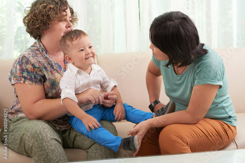 Cheerful lesbian mixed-race couple playing with their little son together