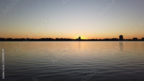 sun setting on the horizon seen from a lake photo