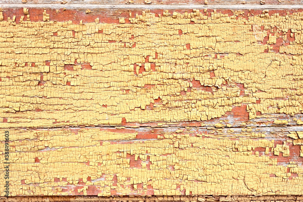 Texture of old wooden wall of abandoned building with peeled yellow paint abstract background.