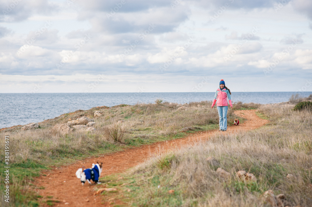 sport healthy girl in track suit playing with her dogs on cold sea shore in spring