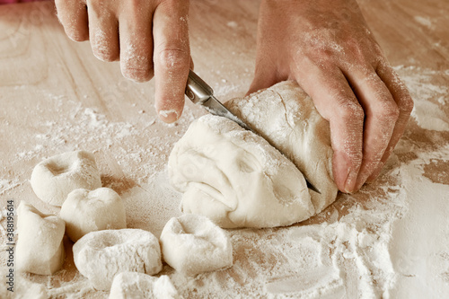 woman chef cuts the dough with a knife, female hands in flour, female chef holds the dough, female hands with a knife in flour