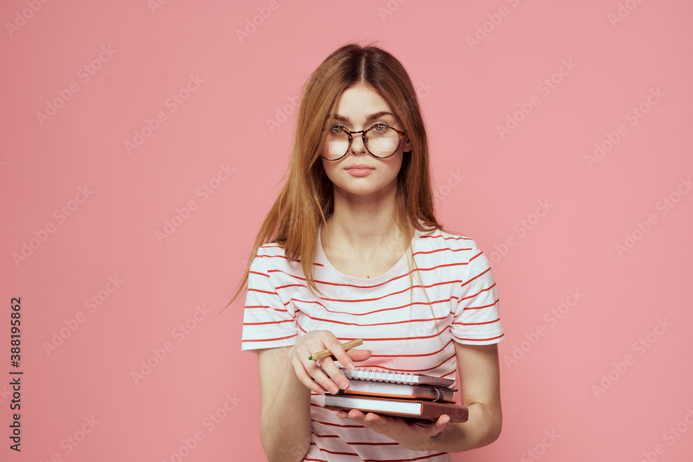 Young female student with books on pink background glasses on face education institute cropped view
