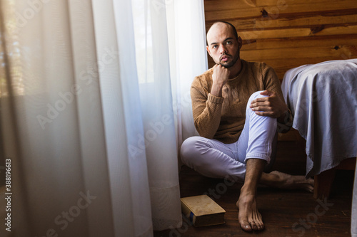 hombre pelón con barba leyendo un libro con un suéter para el frio photo