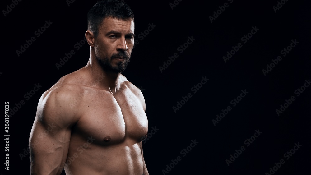 Fototapeta premium Fit and sporty bodybuilder over black background. Sportsman in studio. Sport and fitness concepts.