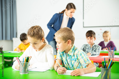 Portrait of schoolchildren sitting in classroom and chatting during lesson. High quality photo