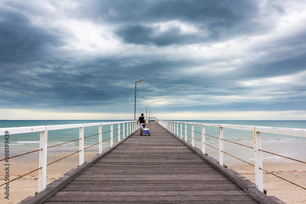 A man walking out with fishing gear on the old largs bay jetty in adelaide south australia on october 26th 2020