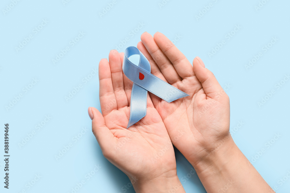 Female hands with awareness ribbon on color background. Diabetes concept