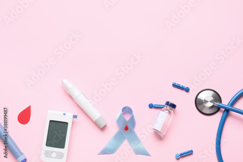 Glucometer with lancet pen, bottle of insulin, stethoscope and awareness ribbon on color background. Diabetes concept