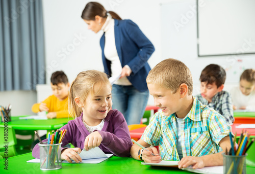 Portrait of schoolchildren sitting in classroom and chatting during lesson. High quality photo