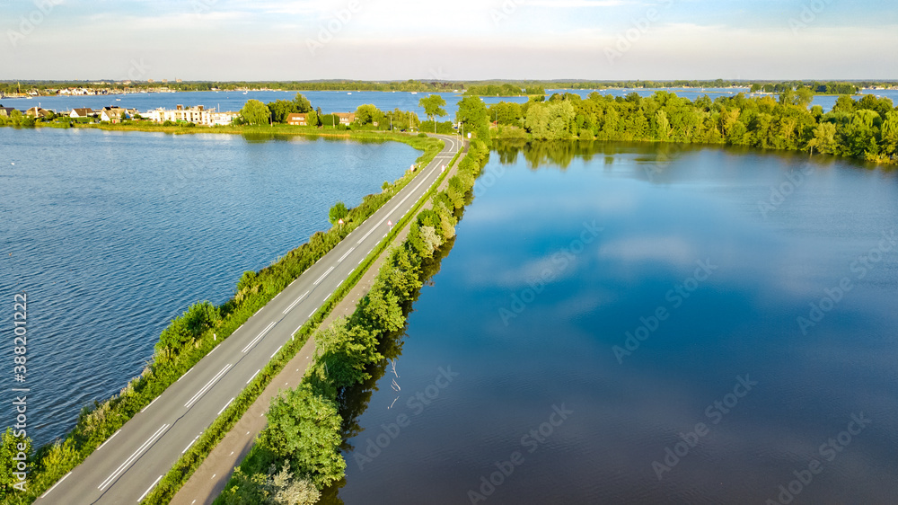 Aerial drone view of motorway road and cycling path on polder dam, cars traffic from above, North Holland, Netherlands
