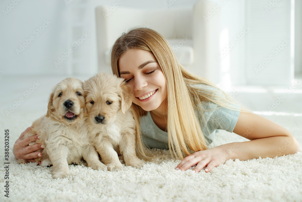 Cute young woman kisses and hugs a Labrador Retriever puppy dog. Love between owner and dog. In the room at home, interior. High quality photo. Cute young woman kisses and hugs a Labrador Retriever puppy dog. Love between owner and dog. In the room at home, interior. High quality photo.