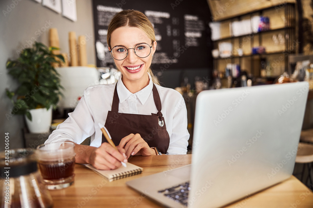 Happy cheerful female in uniform looking at the photo camera in the cafe Happy cheerful female in uniform looking at the photo camera in the cafe
