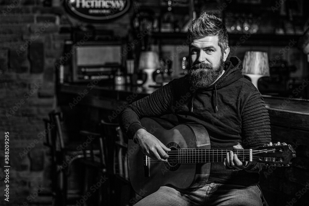 Play the guitar. Beard hipster man sitting in a pub. Music concept. Bearded guitarist plays. Black and white