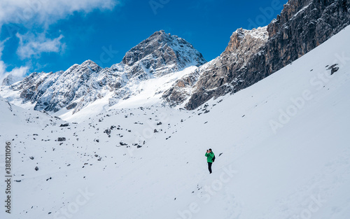 Hiker ascent to the summit. Winter ice and snow climbing in mountains. A success of mountaineer reaching the summit. Outdoor adventure sports in winter alpine moutain landscape. photo