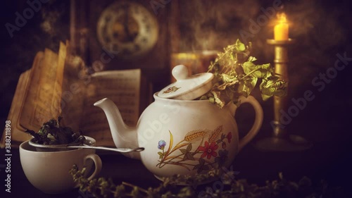 Cup of Tea and Teapot on wooden table with vintage clock, old book and candle burning in the background. Time for Tea concept