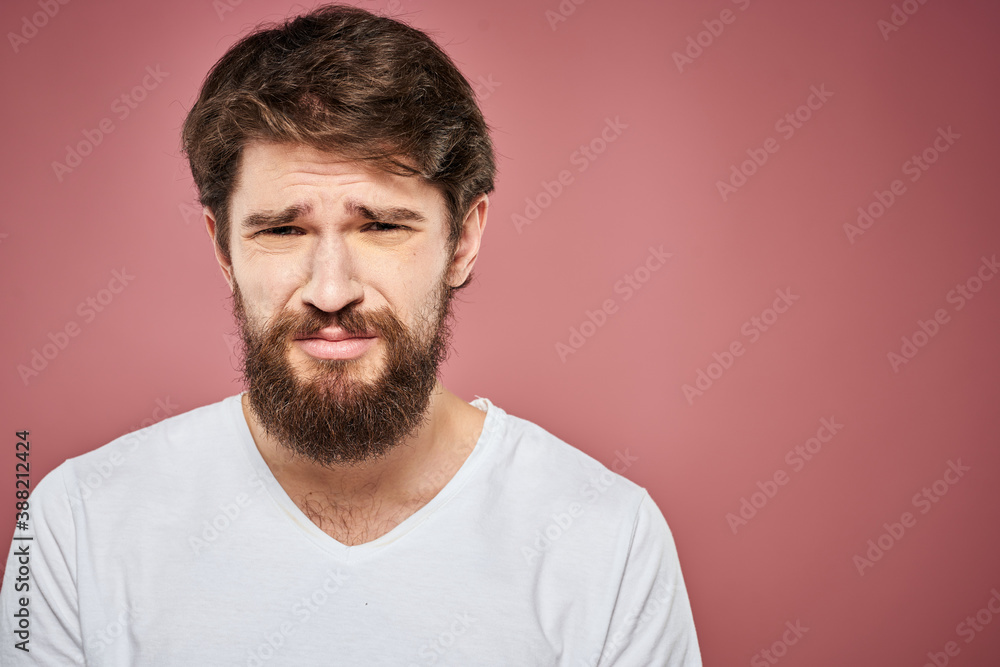 Obraz premium Emotional bearded man in white T-shirt discontent pink background