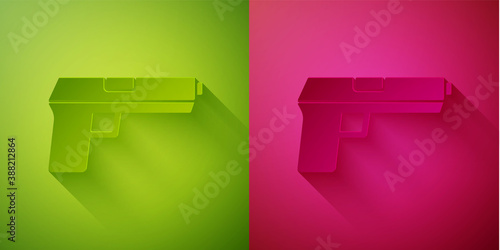 Paper cut Pistol or gun icon isolated on green and pink background. Police or military handgun. Small firearm. Paper art style. Vector.