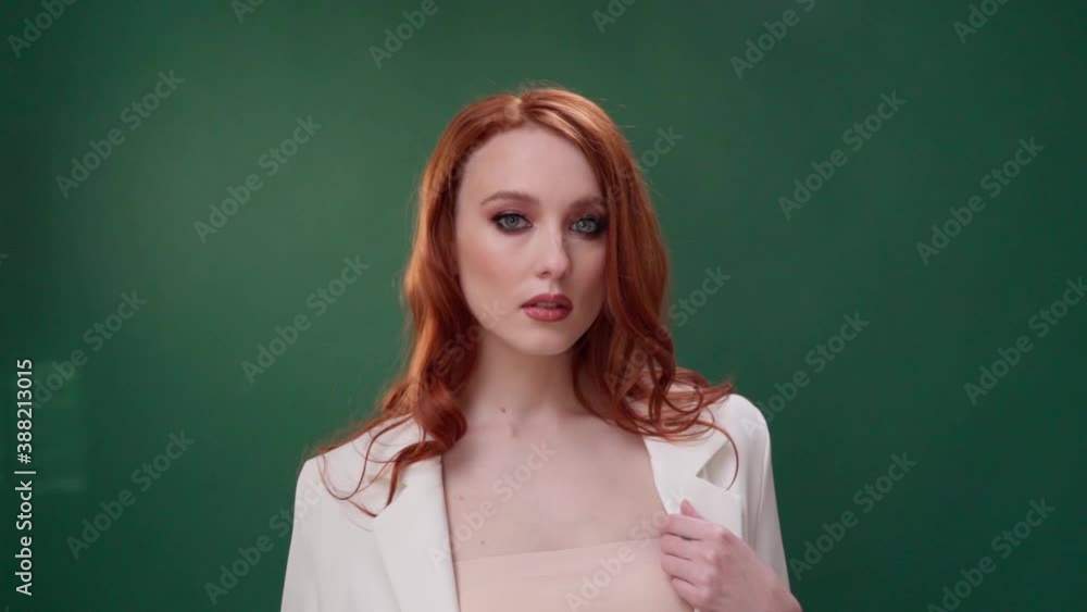 Beautiful fashionable girl with long curly red hair. Girl in the studio on a green background. Advertising, hair products, beauty salon, cosmetics, clothing. Fashion, boutique. Beautiful fashionable girl with long curly red hair. Girl in the studio on a green background. Advertising, hair products, beauty salon, cosmetics, clothing. Fashion, boutique.