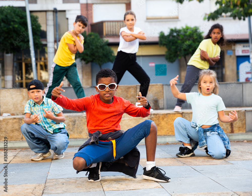 Fototapeta premium Cheerful preteen boys and girls breakdancers dancing on city street on summer day.