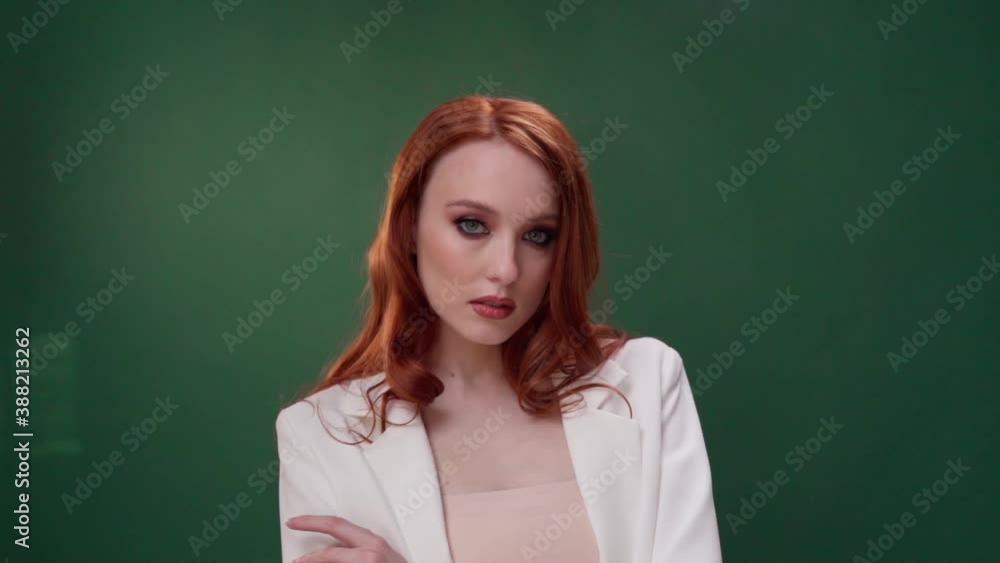 Beautiful fashionable girl with long curly red hair. Girl in the studio on a green background. Advertising, hair products, beauty salon, cosmetics, clothing. Fashion, boutique. Beautiful fashionable girl with long curly red hair. Girl in the studio on a green background. Advertising, hair products, beauty salon, cosmetics, clothing. Fashion, boutique.