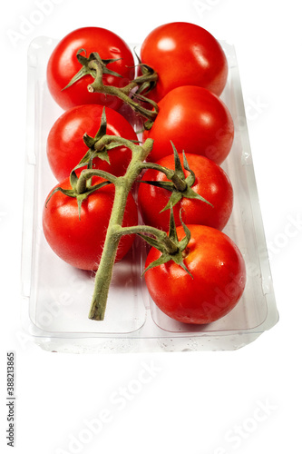Fresh juicy tomato on a vine in a plastic container on a white background. Produce product © mark_gusev