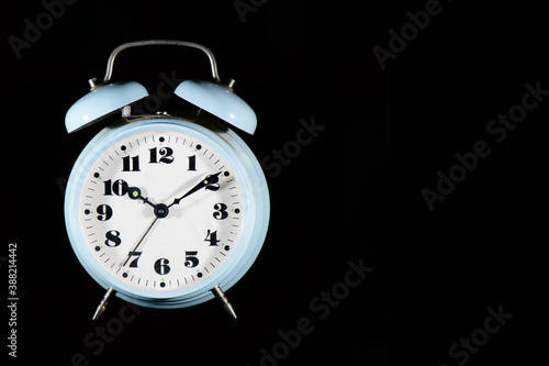Classic table alarm clock in light blue color on a black background