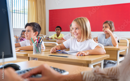 Multiracial group of kids working at class, watching presentation in classroom