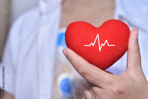 Soft focus of red heart with electrocardiogram in heart diseases patient's hand. Complications of heart arrhythmias may include stroke, sudden death and heart failure and increased risk of blood clots