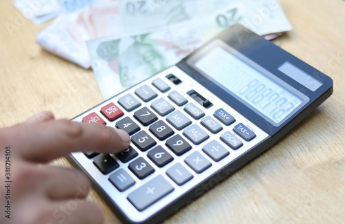 man doing financial transactions with calculator holding money in hand.