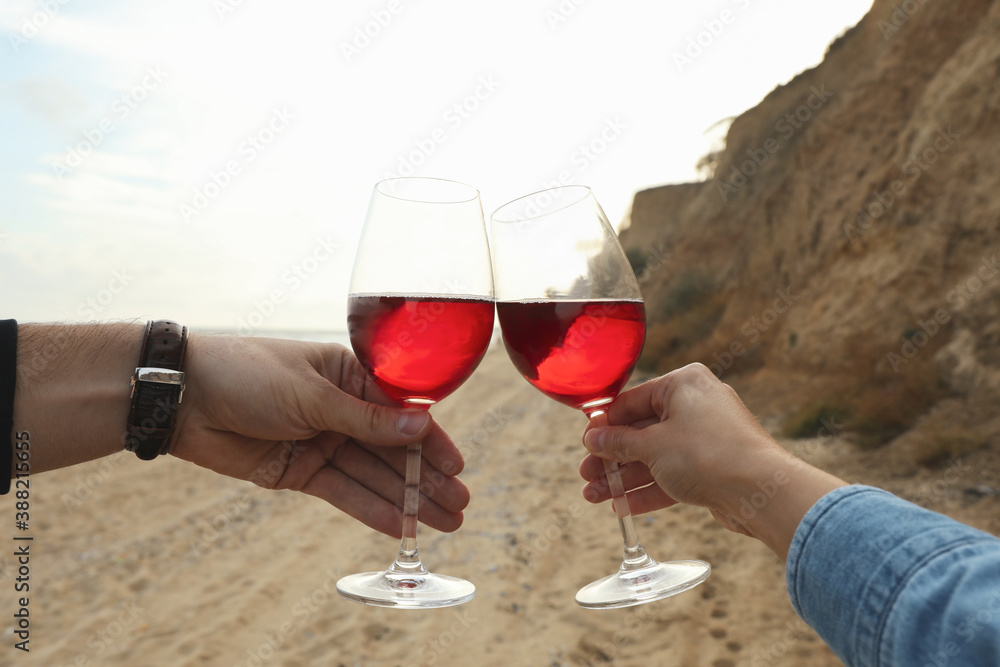 Woman and man cheering with wine on sandy beach