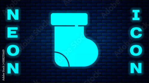 Glowing neon Baby socks clothes icon isolated on brick wall background. Vector.