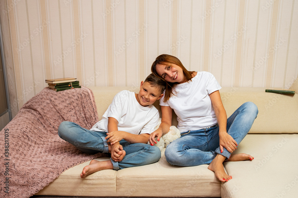 Mother hugging with her smiling son sitting on couch Mother hugging with her smiling son sitting on couch