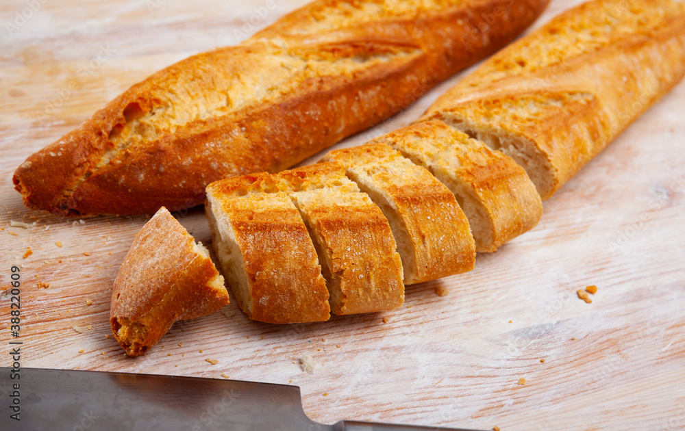 Sliced traditional french baguette on wooden surface
