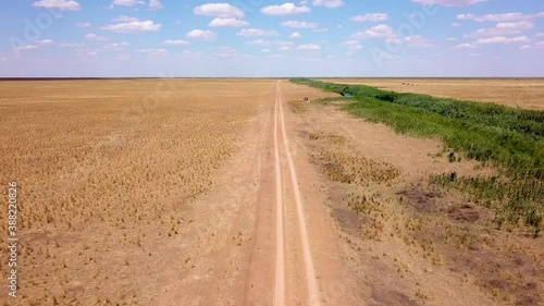 Fly over an empty dusty road via drone in desert or semi-desert region