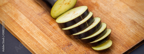 Fresh sliced eggplant on wooden cutting board isolated on black. Cooking ingredients