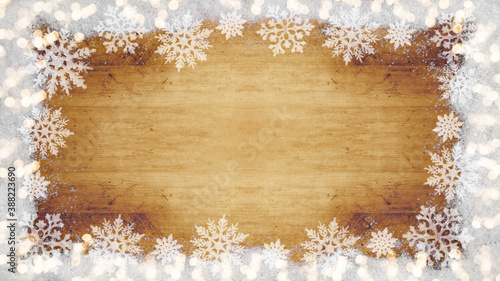 Winter / Advent / Christmas / holiday Background template - Frame made of snow with snowflakes, ice crystals and sparkles bokeh lights on brown wooden texture, top view with space for text