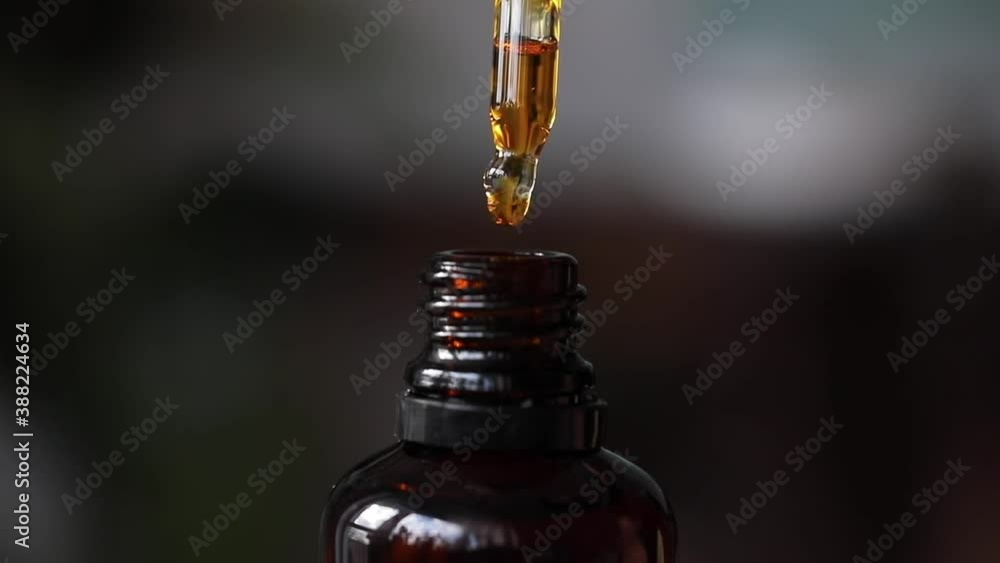 golden light liquid dropper dropping liquid in a bottle close up shot